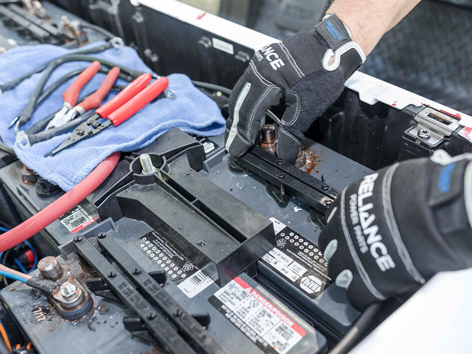 gloved hands maintaining a golf cart battery